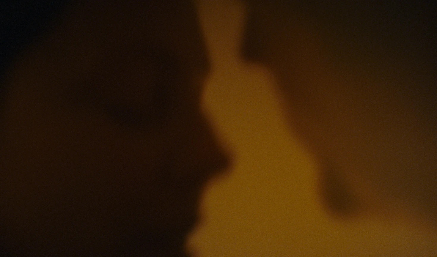Two abstract silhouettes in amber light.