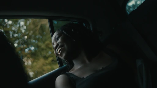 A young person smiling beside a car window.